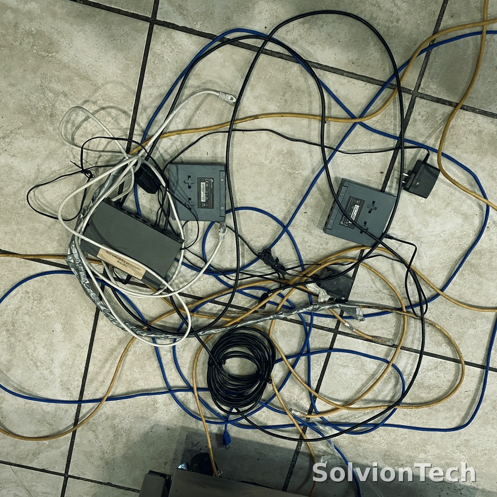 Tangled network cabling and multiple switches on the floor before cleanup